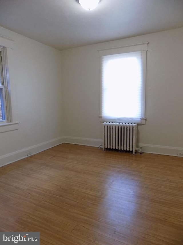 unfurnished room featuring wood-type flooring and radiator