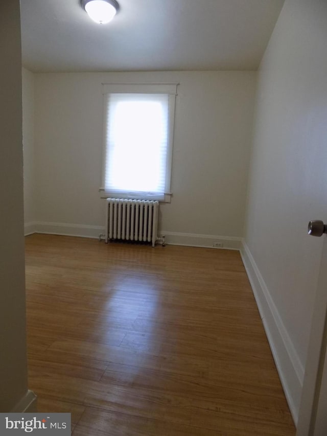 spare room featuring hardwood / wood-style floors and radiator heating unit