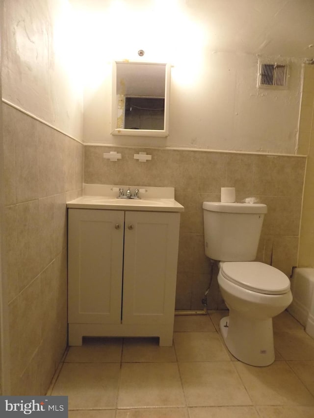 bathroom with tile patterned flooring, vanity, toilet, and tile walls