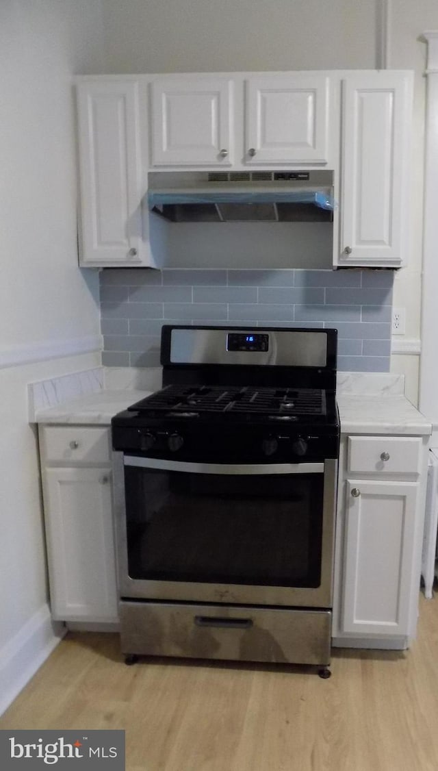 kitchen with tasteful backsplash, light hardwood / wood-style flooring, white cabinets, and stainless steel range with gas stovetop