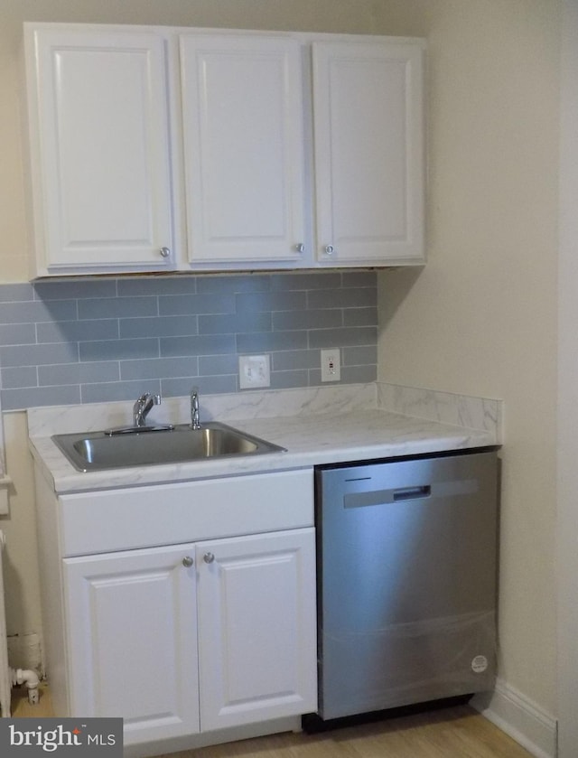 kitchen with decorative backsplash, white cabinets, light stone counters, sink, and dishwasher