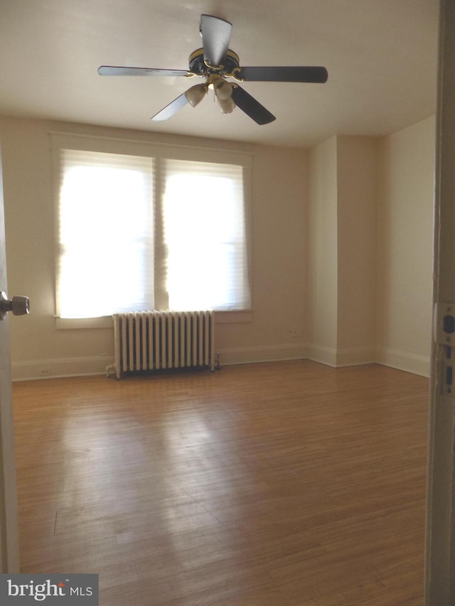 unfurnished room featuring radiator, ceiling fan, plenty of natural light, and light hardwood / wood-style floors