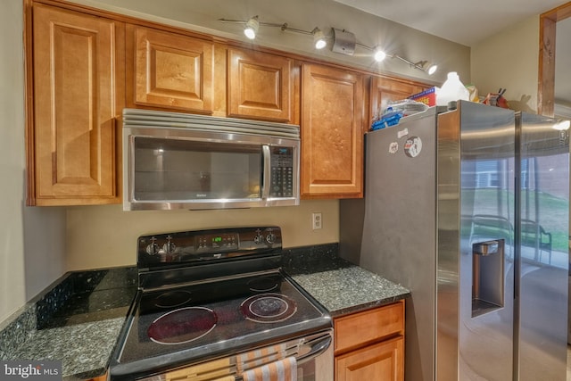 kitchen with dark stone countertops and appliances with stainless steel finishes