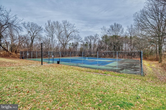 view of tennis court featuring a lawn