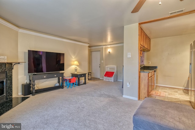 carpeted living room featuring ornamental molding, ceiling fan, and a fireplace