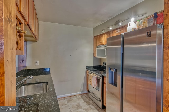 kitchen with light tile patterned floors, appliances with stainless steel finishes, sink, and dark stone counters