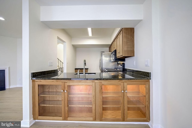 kitchen featuring dark stone countertops, light wood-type flooring, sink, and appliances with stainless steel finishes