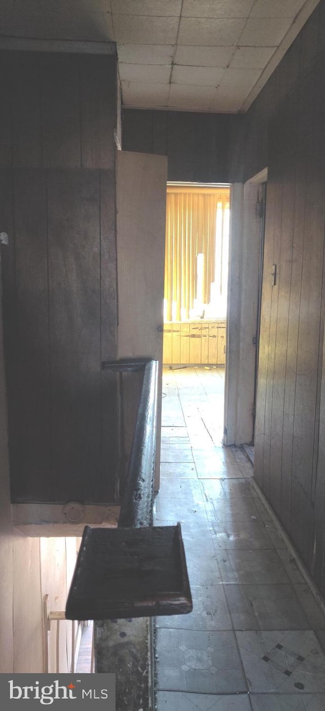 hall with a paneled ceiling and wooden walls