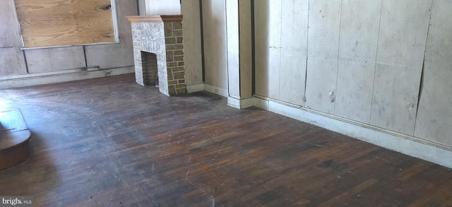 unfurnished living room featuring dark hardwood / wood-style flooring and a brick fireplace