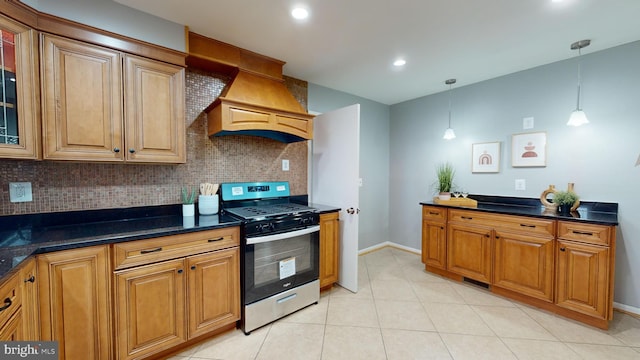 kitchen featuring pendant lighting, stainless steel gas stove, decorative backsplash, and dark stone counters