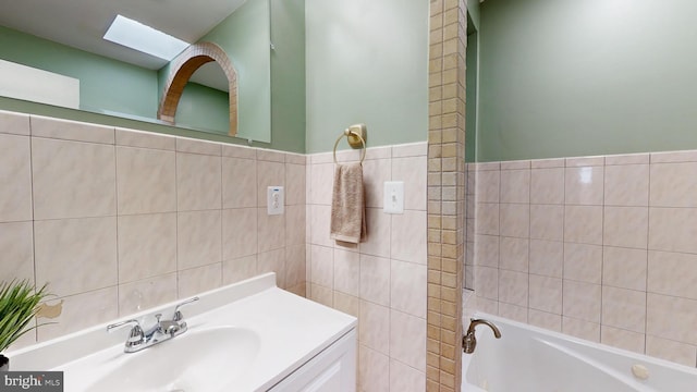 bathroom with vanity, a skylight, and a tub