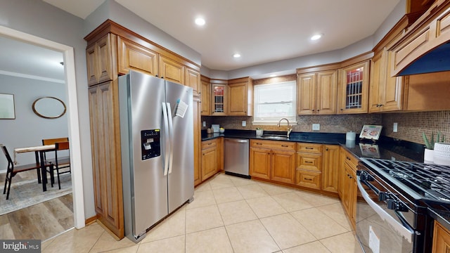 kitchen with sink, backsplash, light hardwood / wood-style floors, appliances with stainless steel finishes, and ornamental molding