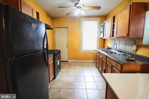 kitchen featuring sink, light tile patterned floors, ceiling fan, and black appliances