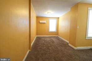 corridor with a wall mounted AC and dark carpet