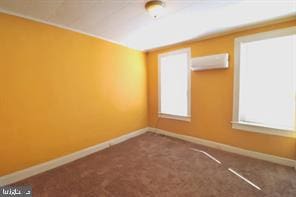 carpeted empty room featuring an AC wall unit