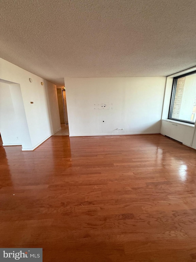 empty room with a textured ceiling and hardwood / wood-style flooring