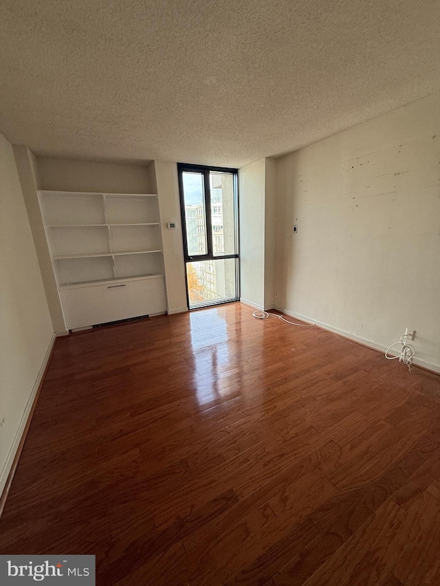 spare room featuring wood-type flooring and a textured ceiling