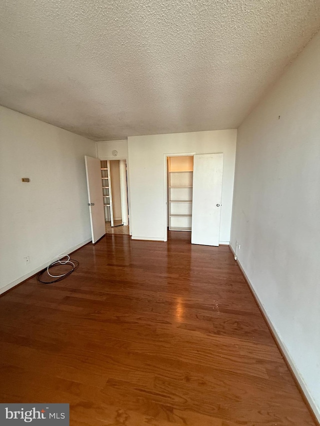 empty room with dark hardwood / wood-style flooring and a textured ceiling