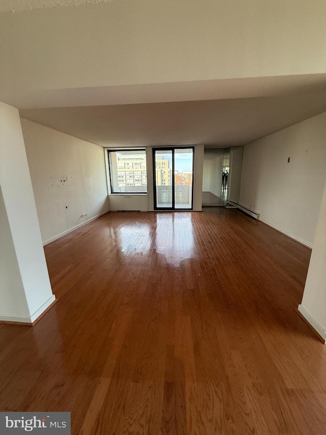 empty room with baseboard heating and hardwood / wood-style flooring