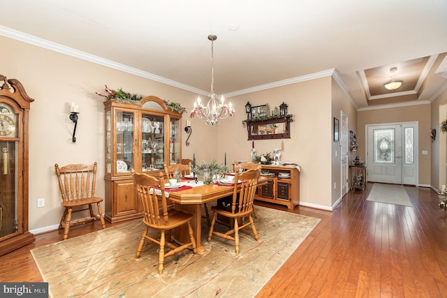 dining area with hardwood / wood-style floors, an inviting chandelier, and ornamental molding