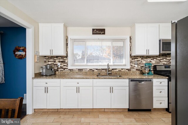 kitchen featuring tasteful backsplash, white cabinetry, sink, and appliances with stainless steel finishes