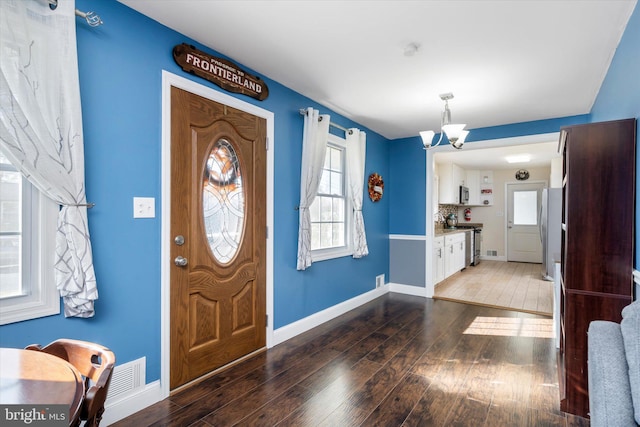 entryway featuring an inviting chandelier and dark wood-type flooring