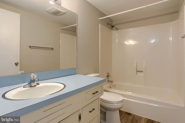 full bathroom with hardwood / wood-style floors, vanity,  shower combination, and toilet