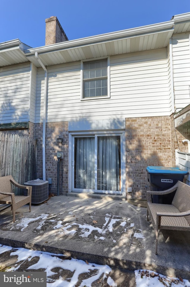 snow covered house with a patio and central air condition unit