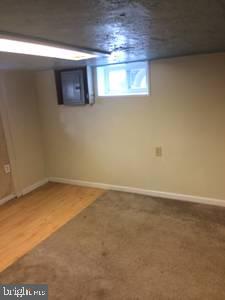 basement with electric panel and wood-type flooring