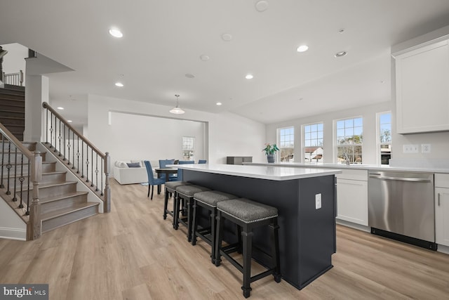 kitchen featuring a center island, dishwasher, light hardwood / wood-style flooring, a kitchen bar, and white cabinets