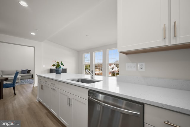 kitchen featuring stainless steel dishwasher, white cabinets, light stone counters, and sink