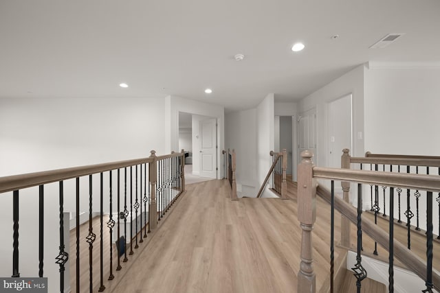 corridor with light hardwood / wood-style floors and ornamental molding