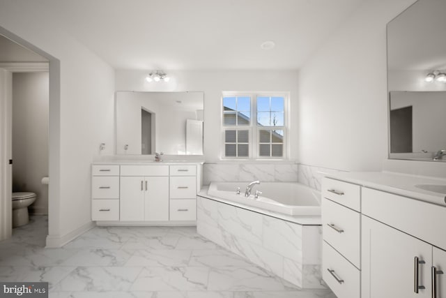 bathroom with vanity, a relaxing tiled tub, and toilet