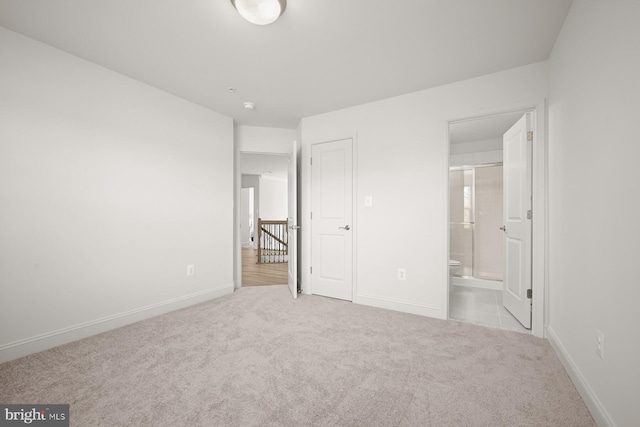 unfurnished bedroom featuring light carpet and ensuite bath