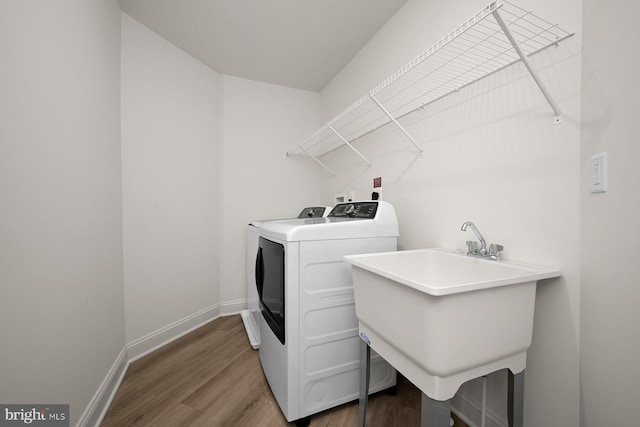 laundry area featuring wood-type flooring, separate washer and dryer, and sink