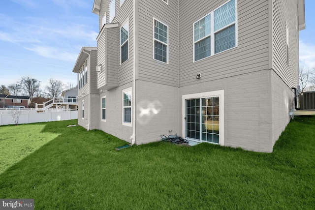 rear view of property with central AC unit and a lawn