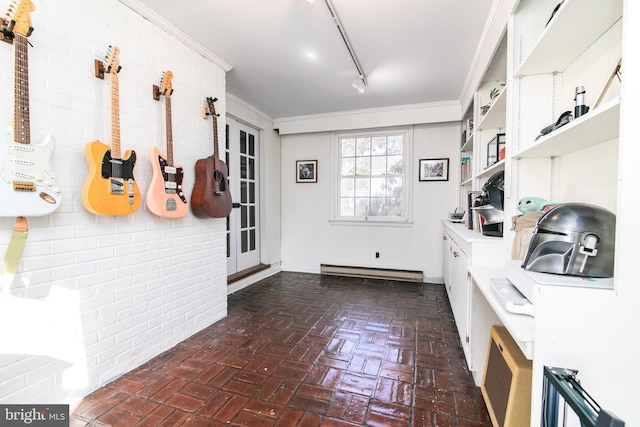 interior space with brick floor, rail lighting, a baseboard heating unit, and ornamental molding