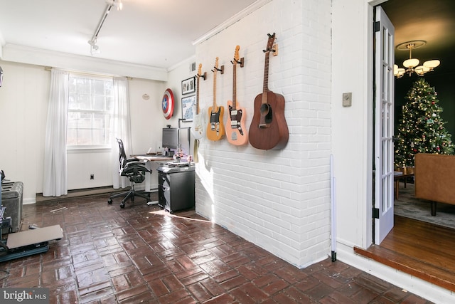 office featuring brick floor, ornamental molding, track lighting, and an inviting chandelier