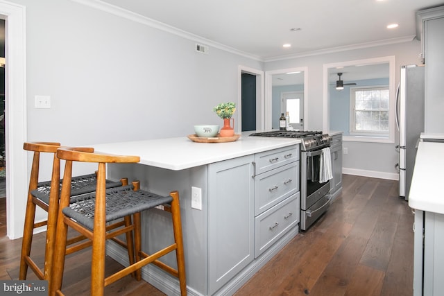 kitchen with stainless steel appliances, visible vents, ornamental molding, and a kitchen bar