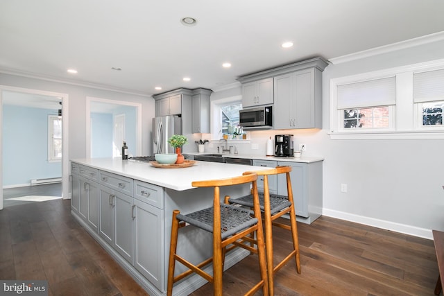 kitchen with stainless steel appliances, gray cabinets, light countertops, and a kitchen bar