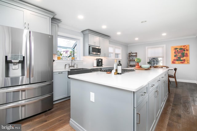 kitchen featuring a center island, crown molding, gray cabinetry, appliances with stainless steel finishes, and a sink