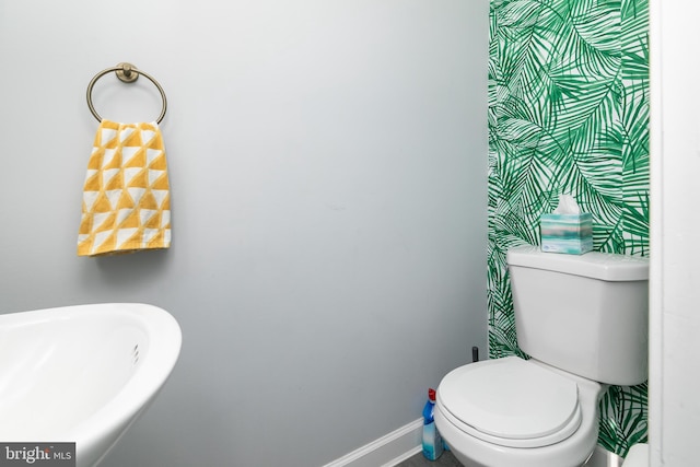 bathroom with a sink, toilet, and baseboards