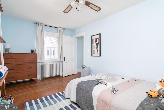 bedroom featuring ceiling fan, radiator heating unit, and wood finished floors