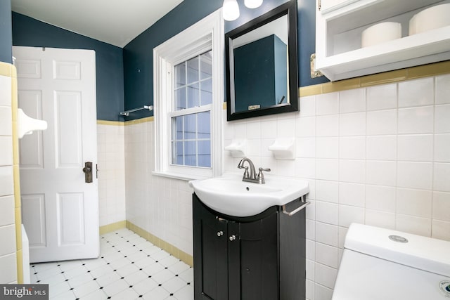 bathroom featuring toilet, vanity, and tile walls