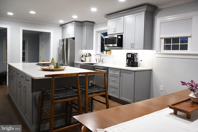 kitchen with recessed lighting, gray cabinetry, a kitchen island, light countertops, and appliances with stainless steel finishes