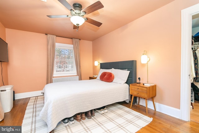 bedroom featuring radiator, ceiling fan, baseboards, and wood finished floors