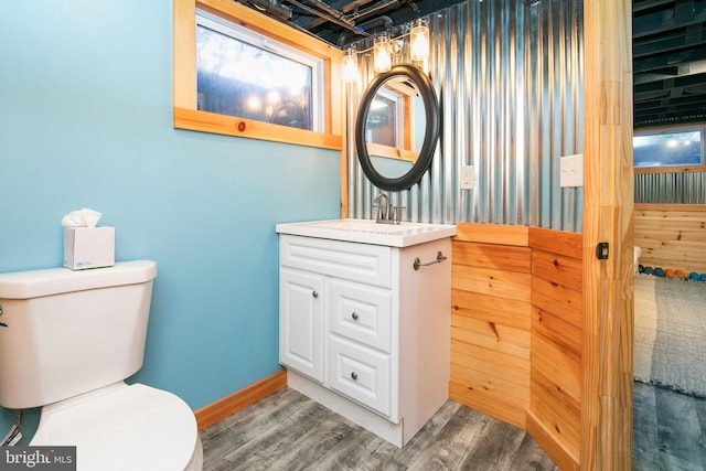 half bathroom featuring toilet, baseboards, wood finished floors, and vanity