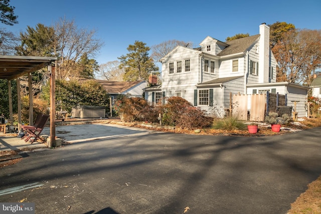 view of front of home with a chimney, fence, and a hot tub