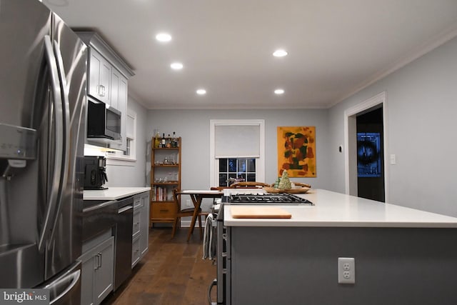 kitchen featuring a kitchen island, light countertops, appliances with stainless steel finishes, dark wood-style floors, and crown molding