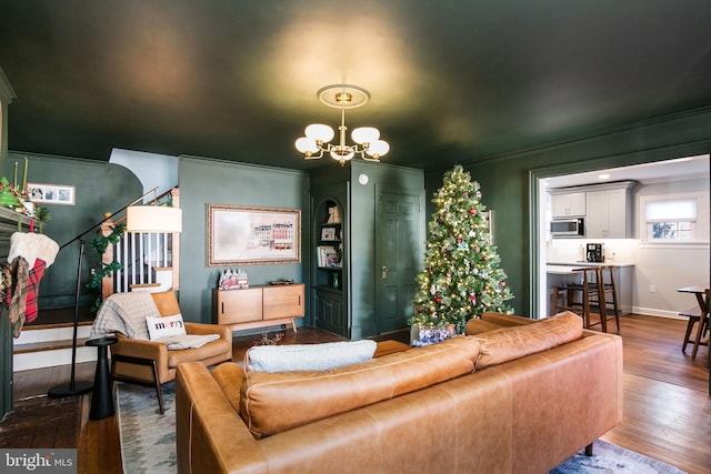 living area featuring dark wood-style flooring, stairway, baseboards, and an inviting chandelier